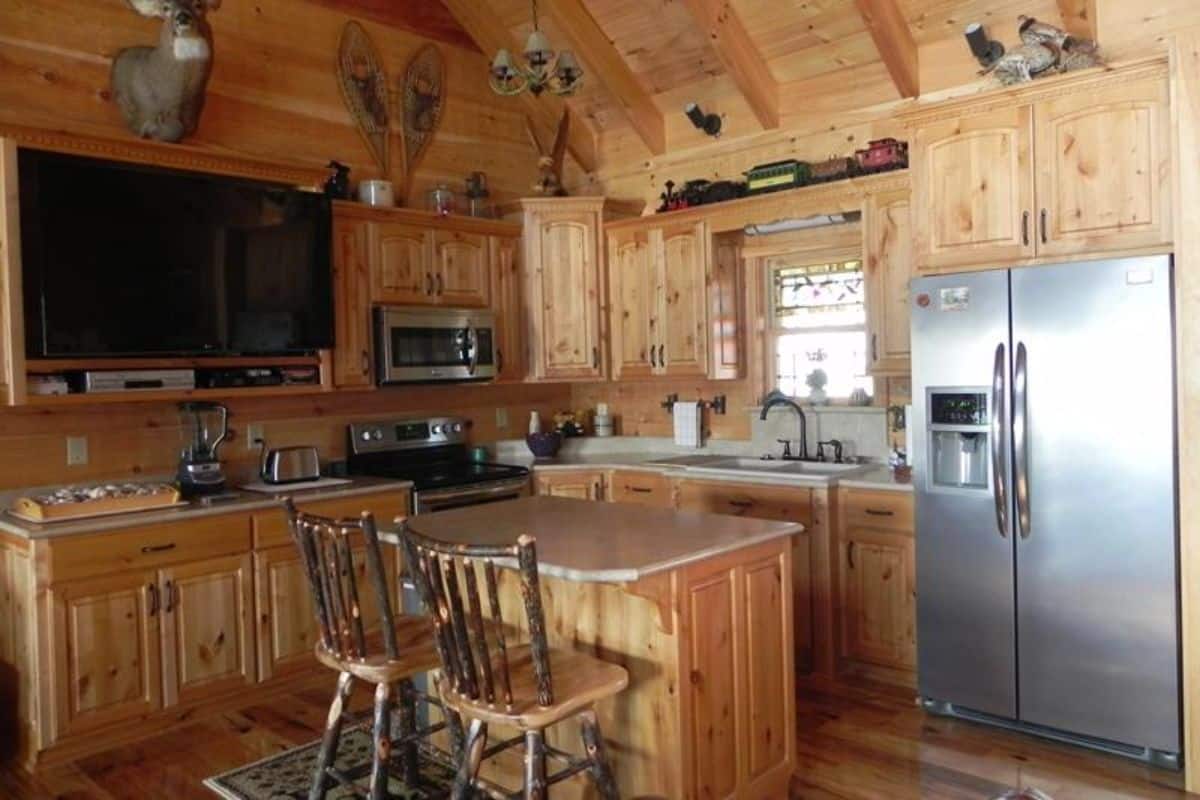 highback wood stools at island bar in kitchen with stainless steel refrigerator