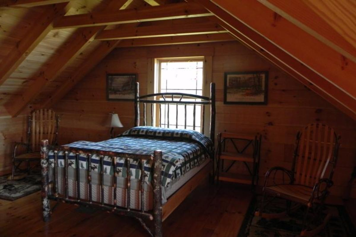 wood bed frame under loft rafter with window behind bed