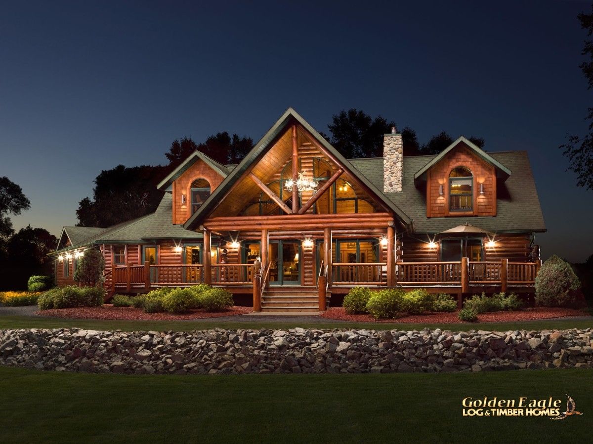 front of log cabin with rock wall at base after dark