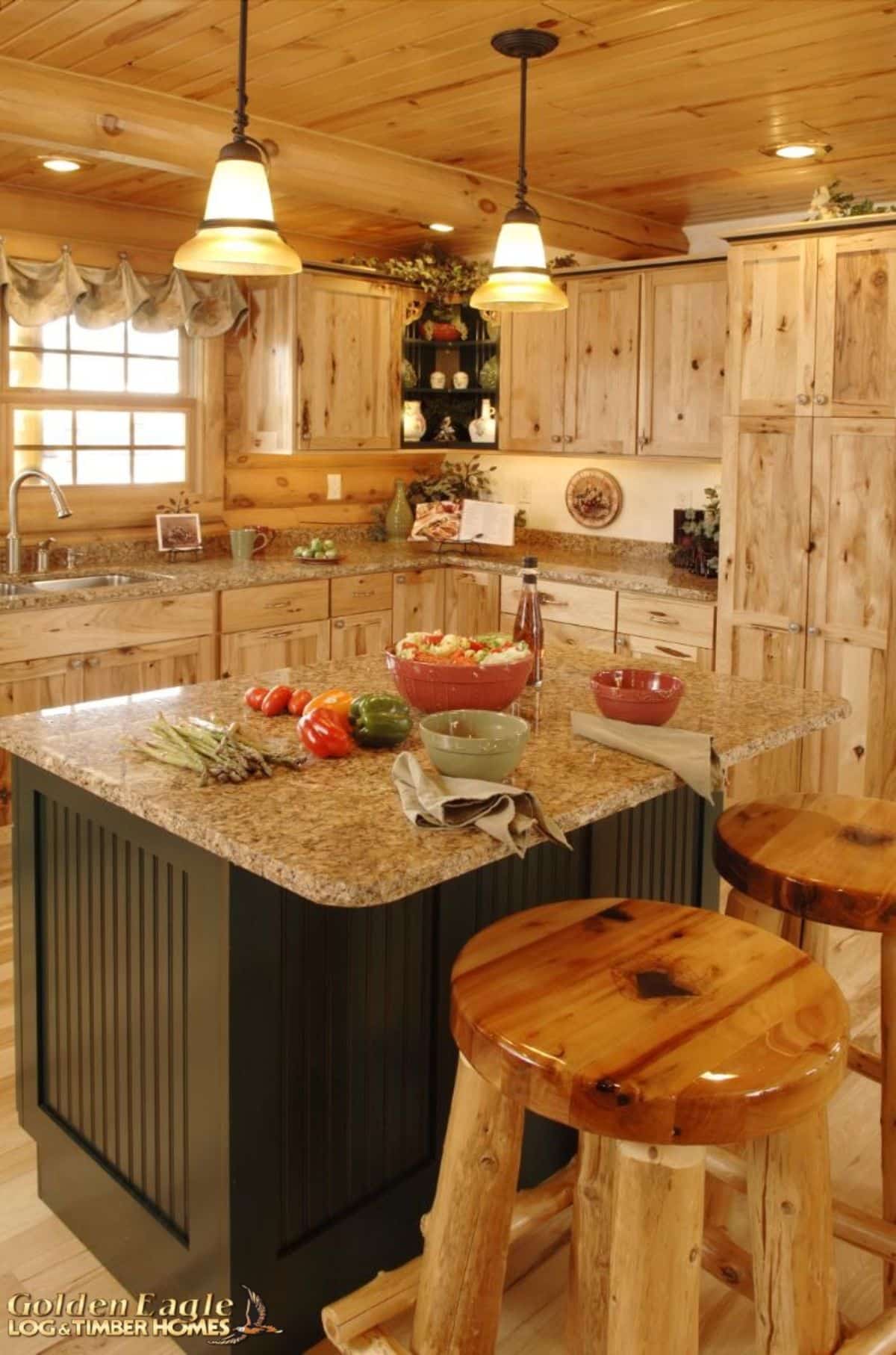 view across island into kitchen with light wood cabinets