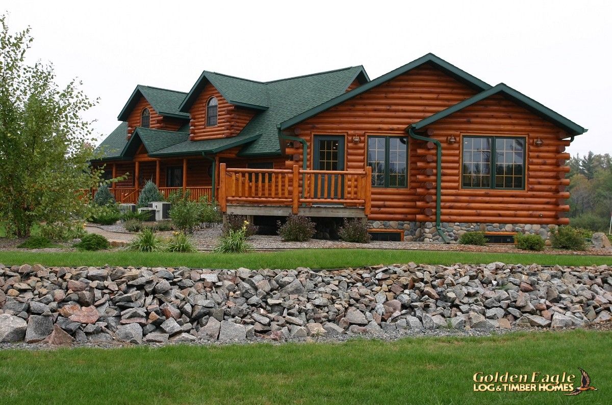 side of log cabin showing rock wall around edge of yard