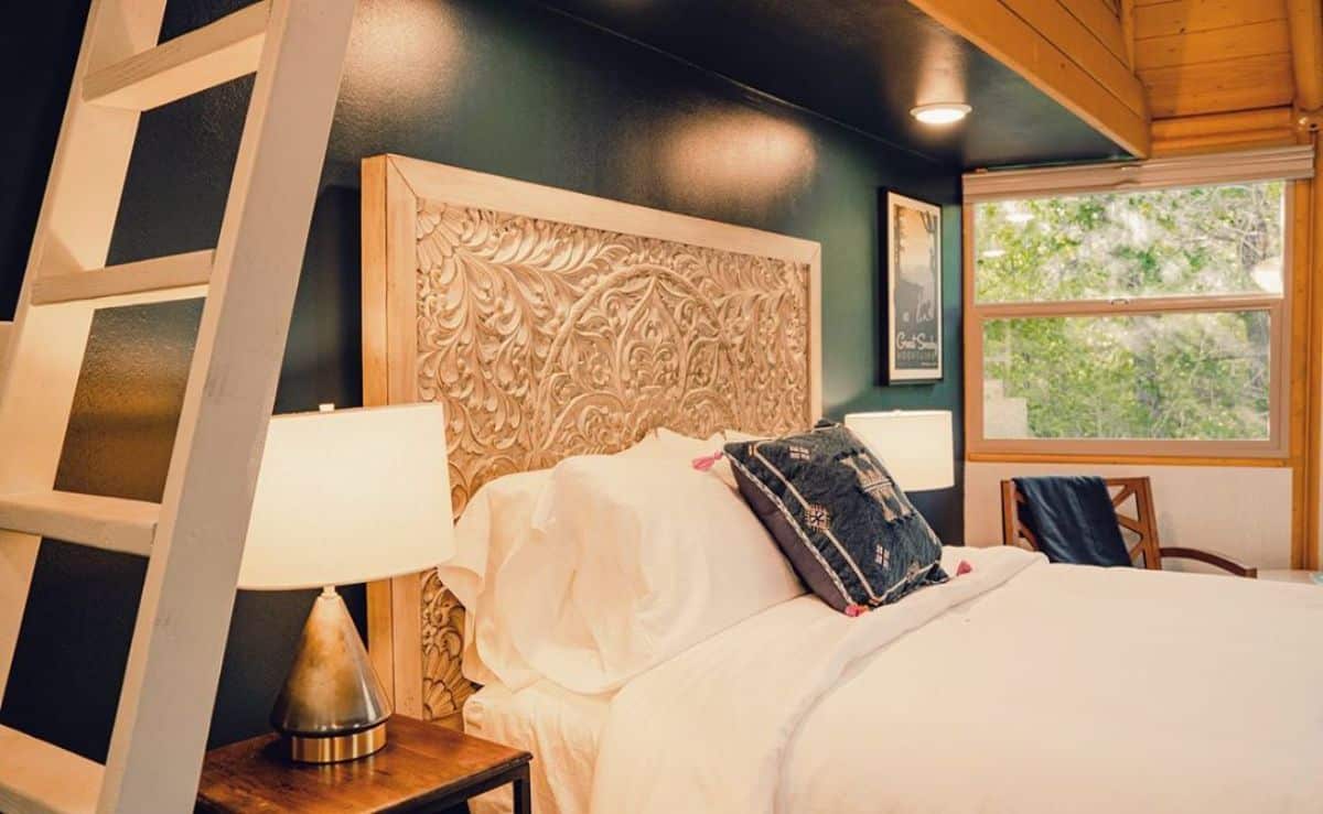 ornate headboard against blue wall with white bedding