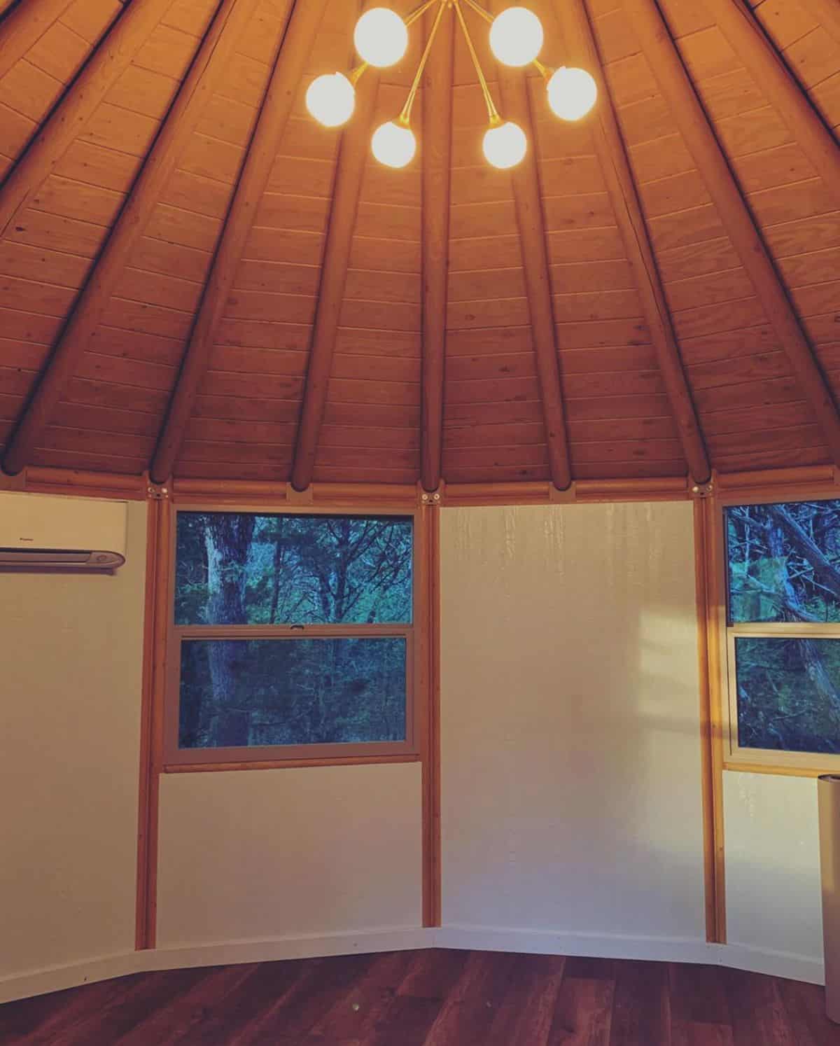 rounded living space inside a yurt with chandelier hanging from ceiling