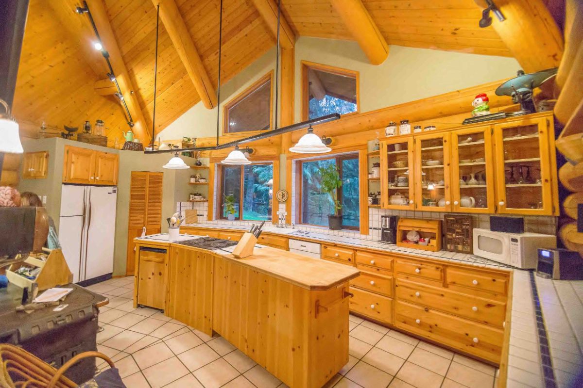 custom wood cabinets in log cabin with cream tile floor beneath island