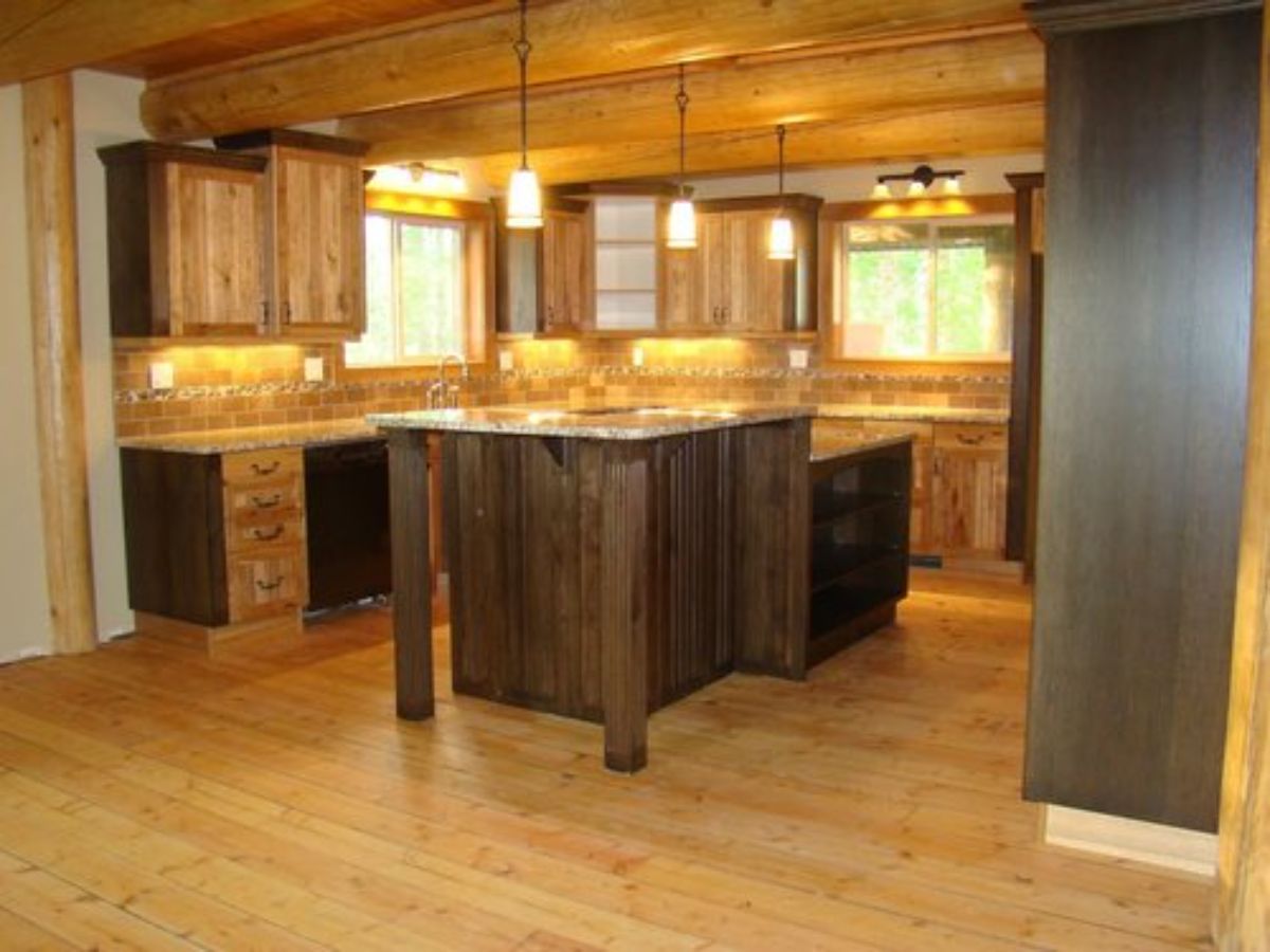 view into cabin kitchen with dark wood island bar in center