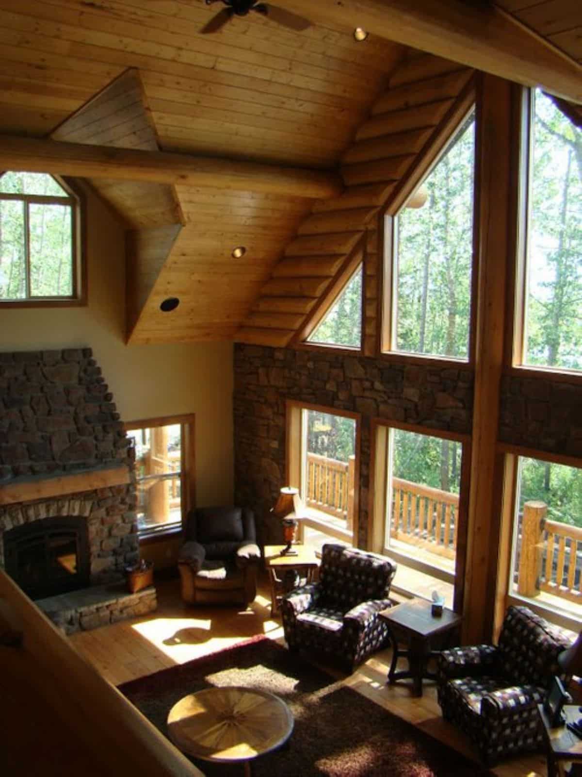 view of log cabin living room and wall of windows from loft