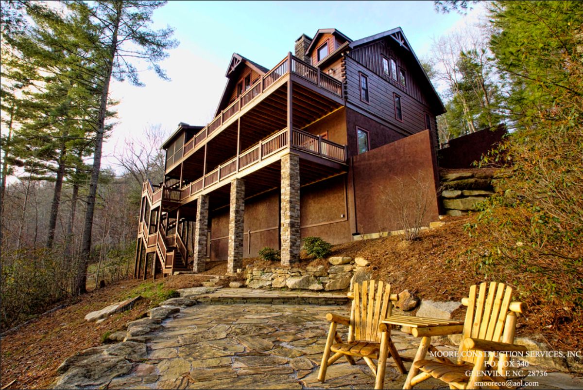 back of cabin showing tall columns beneath covered porches on top levels