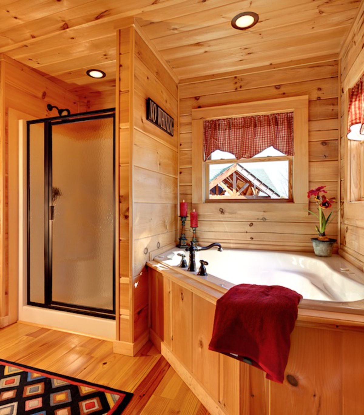soaking tub with wooden surround next to glass door shower