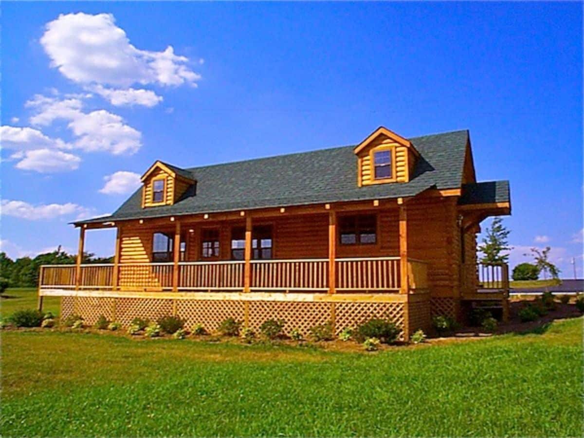 front of log cabin with covered porch and green roof