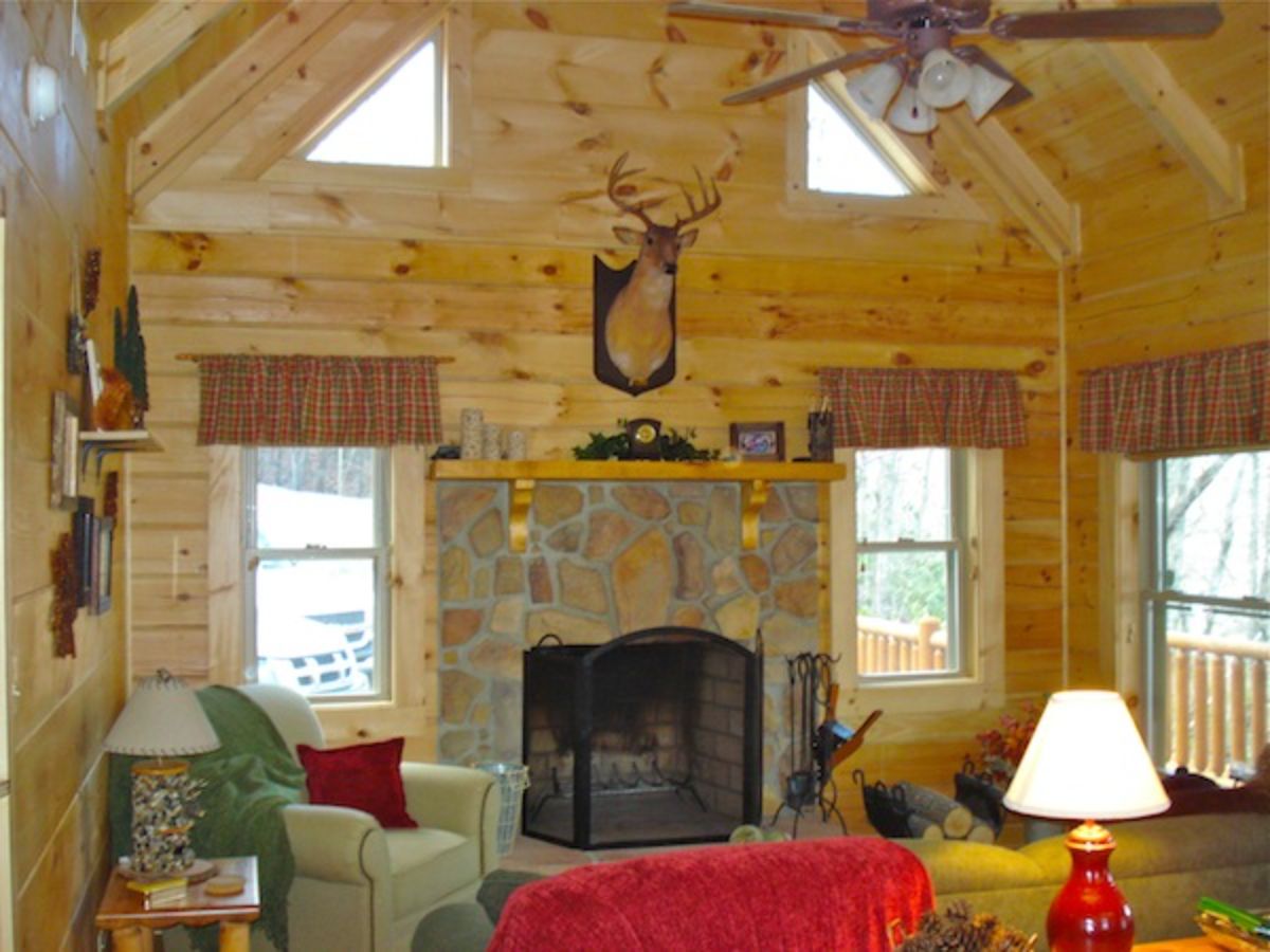 stone fireplace with black iron front between two windows with red sofa in foreground