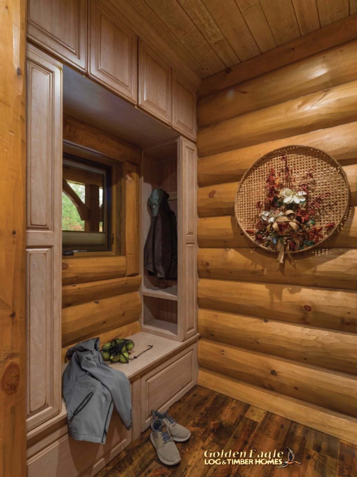 mud room with bench beneath window and round log walls