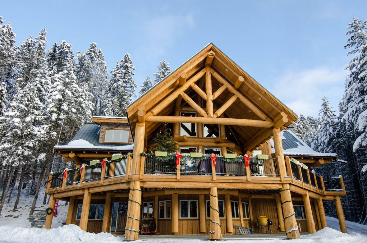 holiday garland and bows on porch railing on top level of log cabin