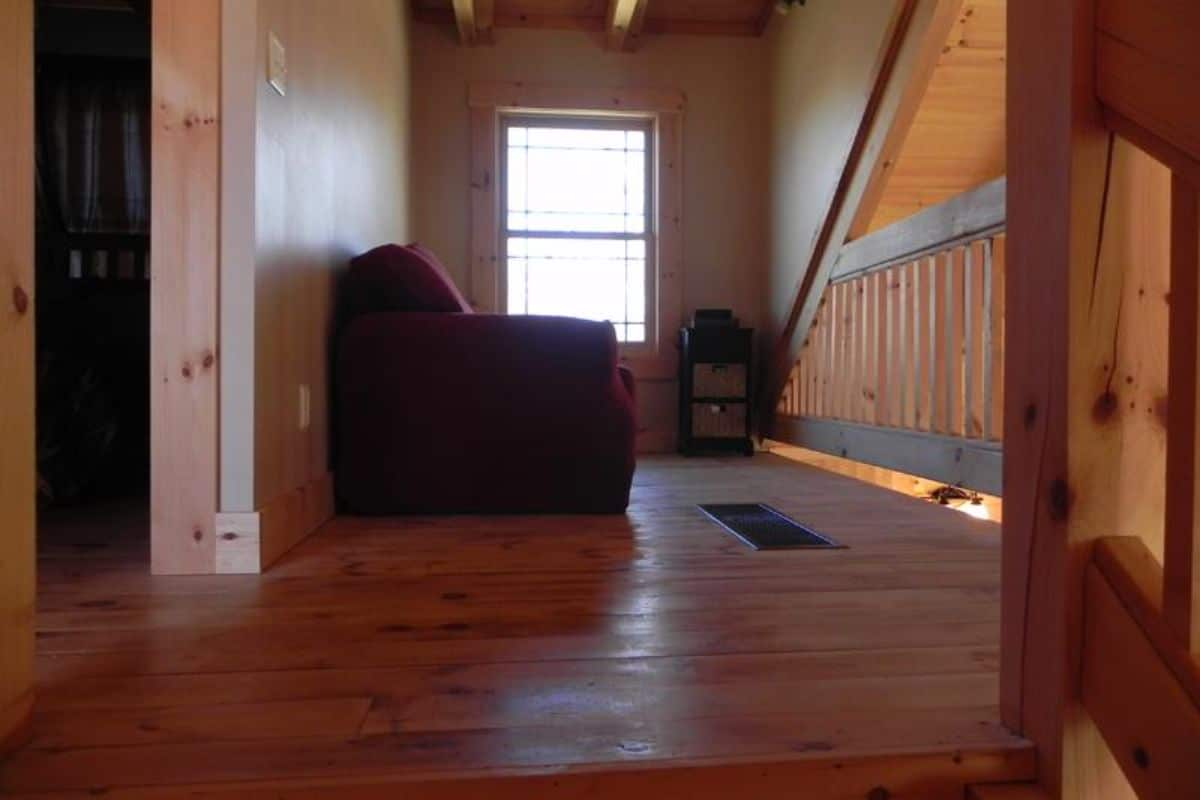 sofa against wall in small loft space inside cabin