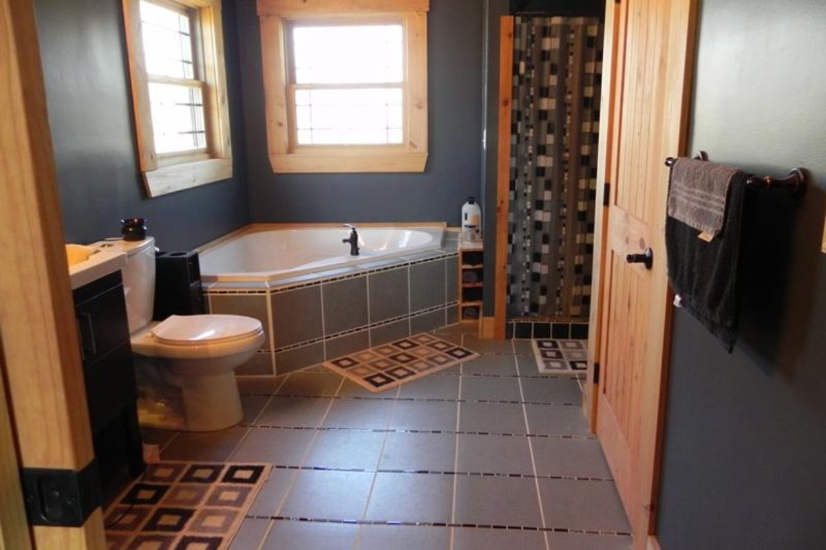 gray tile on floors and surrounding soaking tub in corner of room