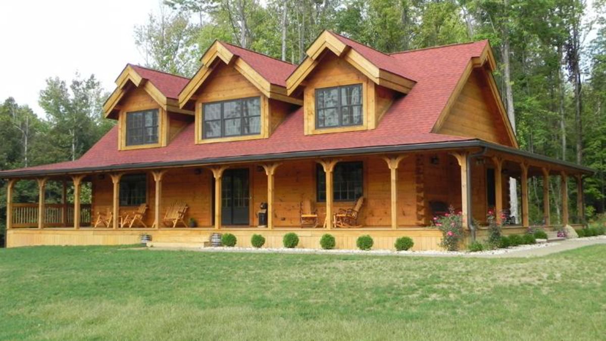 front of log cabin with covered porch and three dormer windows