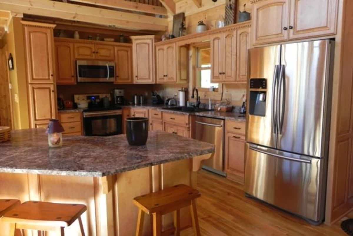 corner kitchen in cabin with stainless steel appliances and small island bar with wood stools