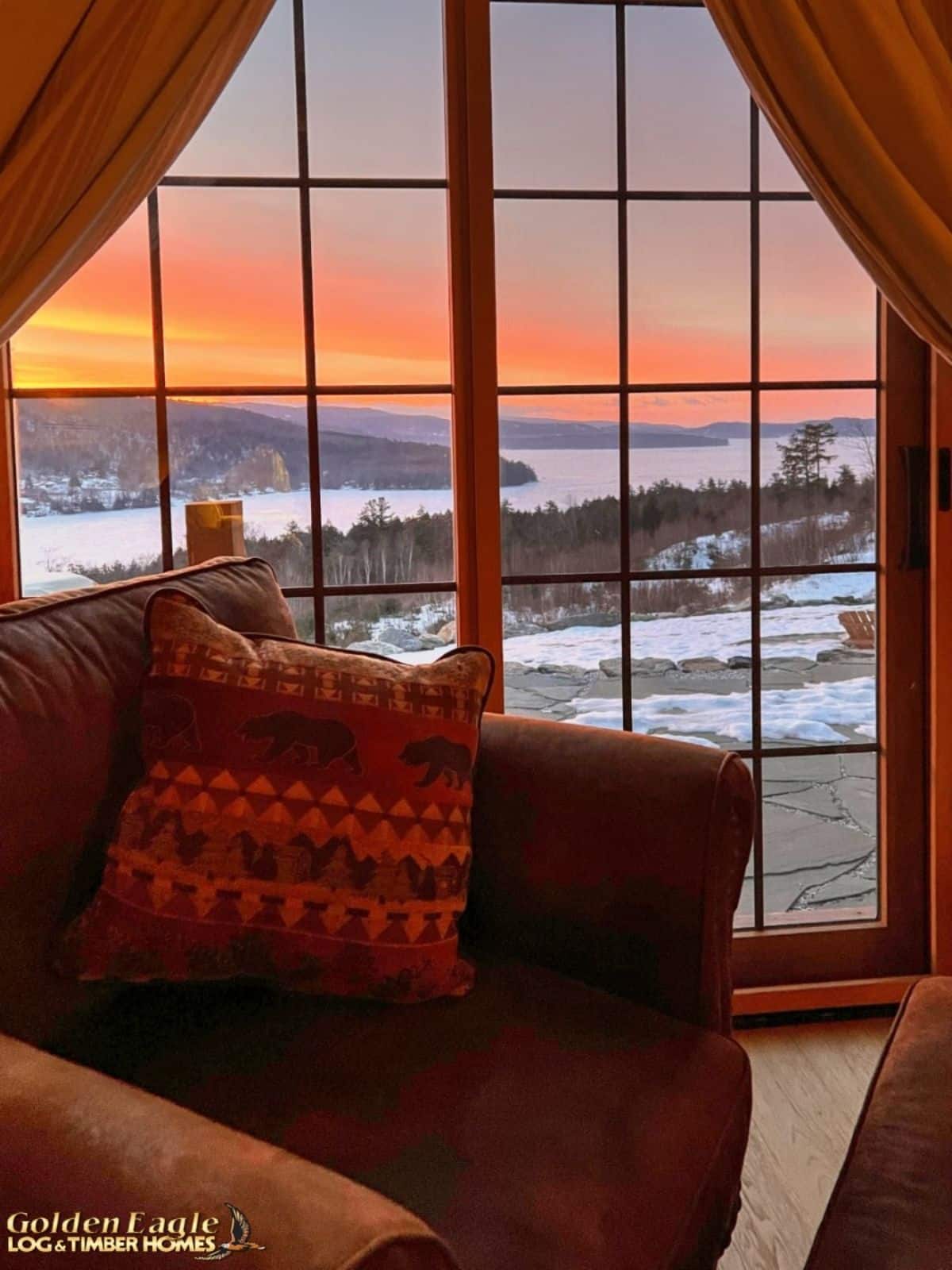 sunset view over snow out picture window by brown chair