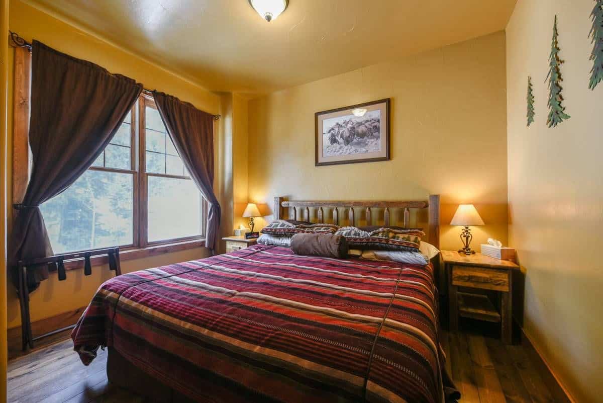 dark red and orange striped bedding on bed with yellow walls in background