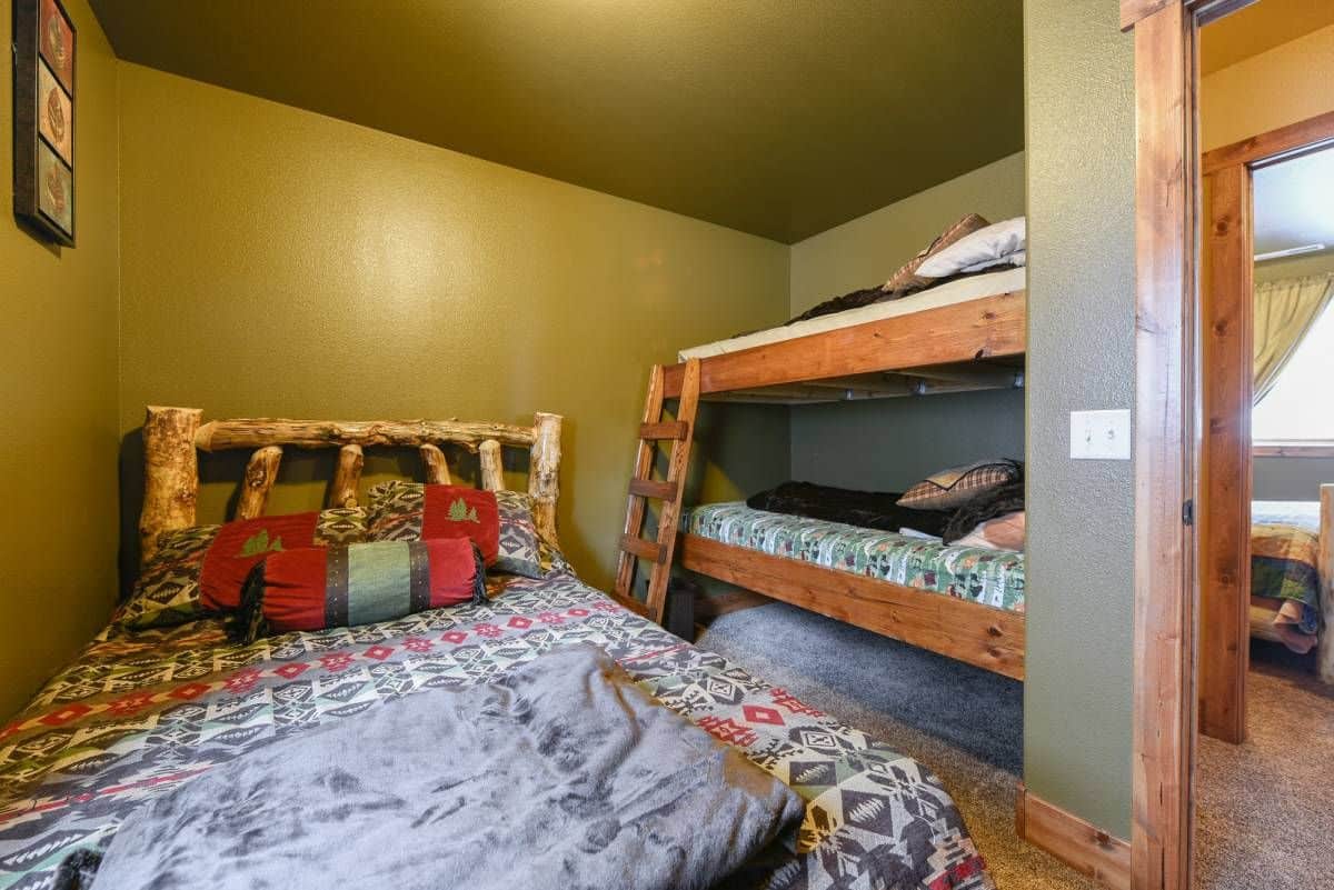 bunk beds against wall in cabin bedroom by larger bed on floor