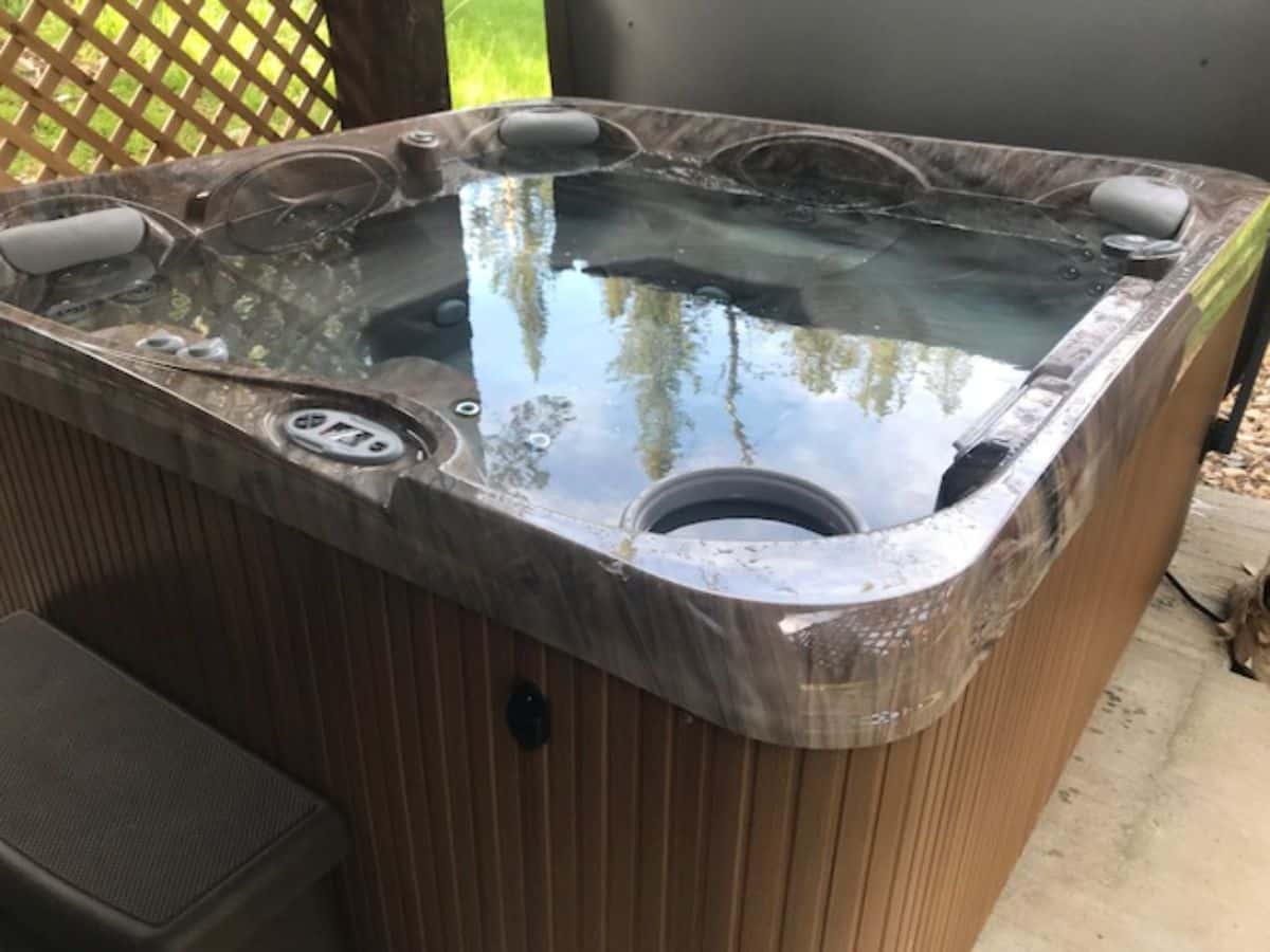 gray hot tub with wood surround on concrete slab