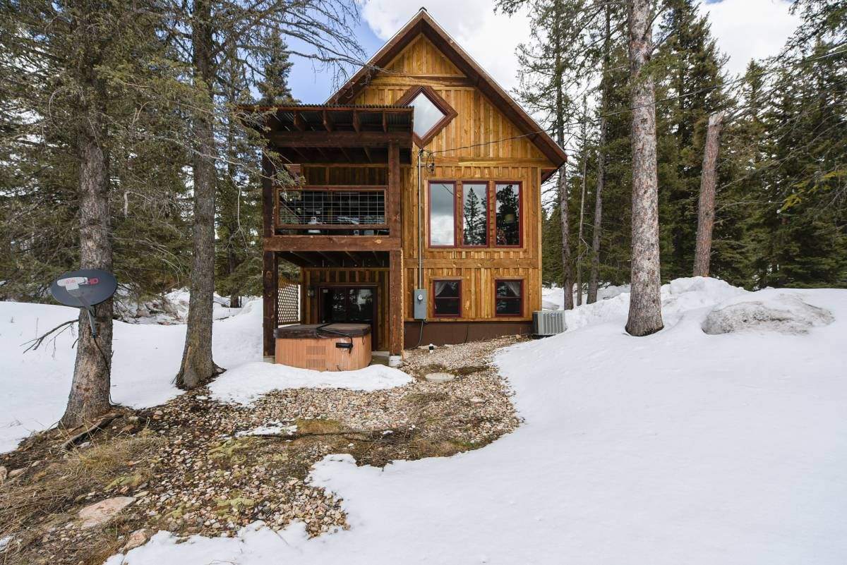 back of cabin with two decks and hot tub on bottom deck