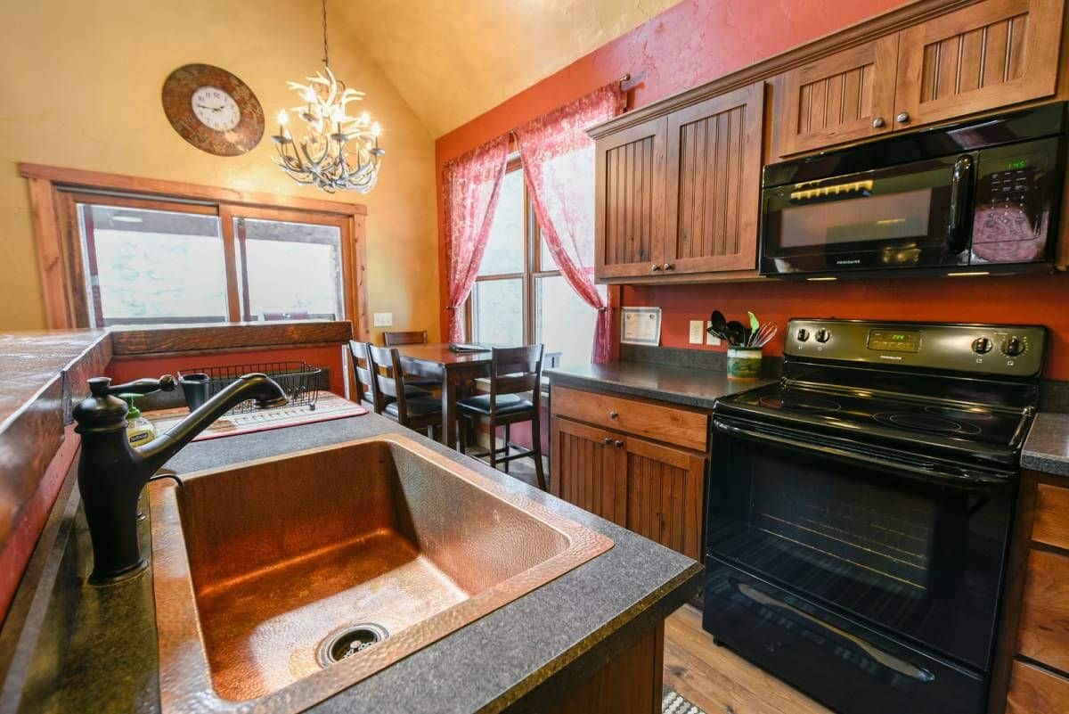 deep copper sink in island of kitchen with black stove in background