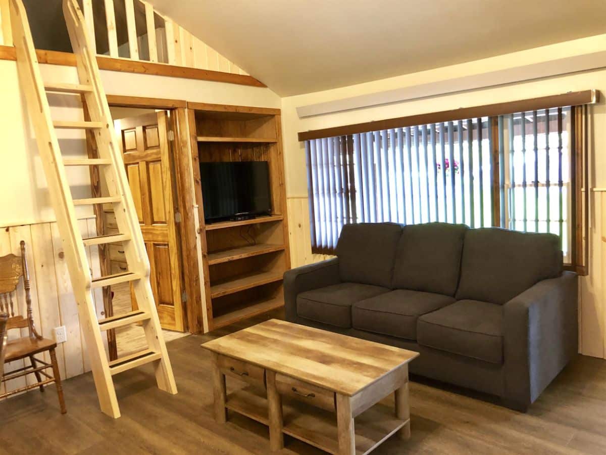 gray couch beside windows with wood coffee table by loft ladder