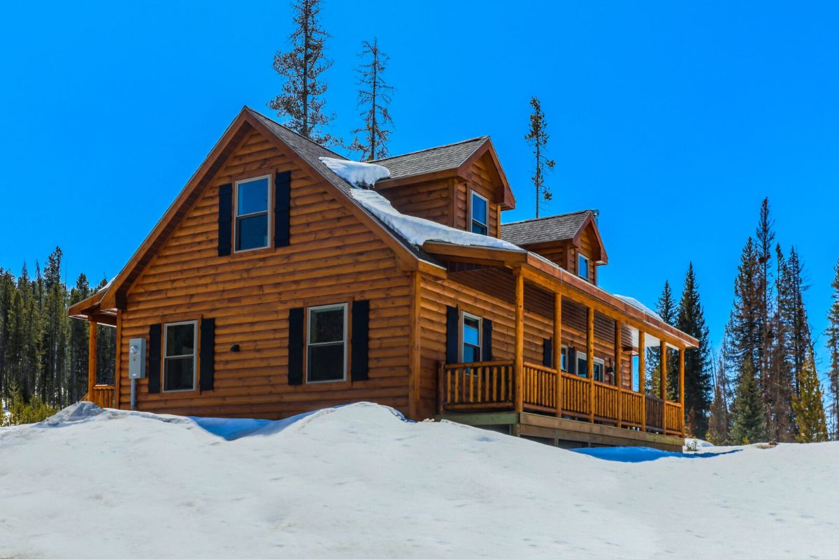 light wood cabin with porch in snow