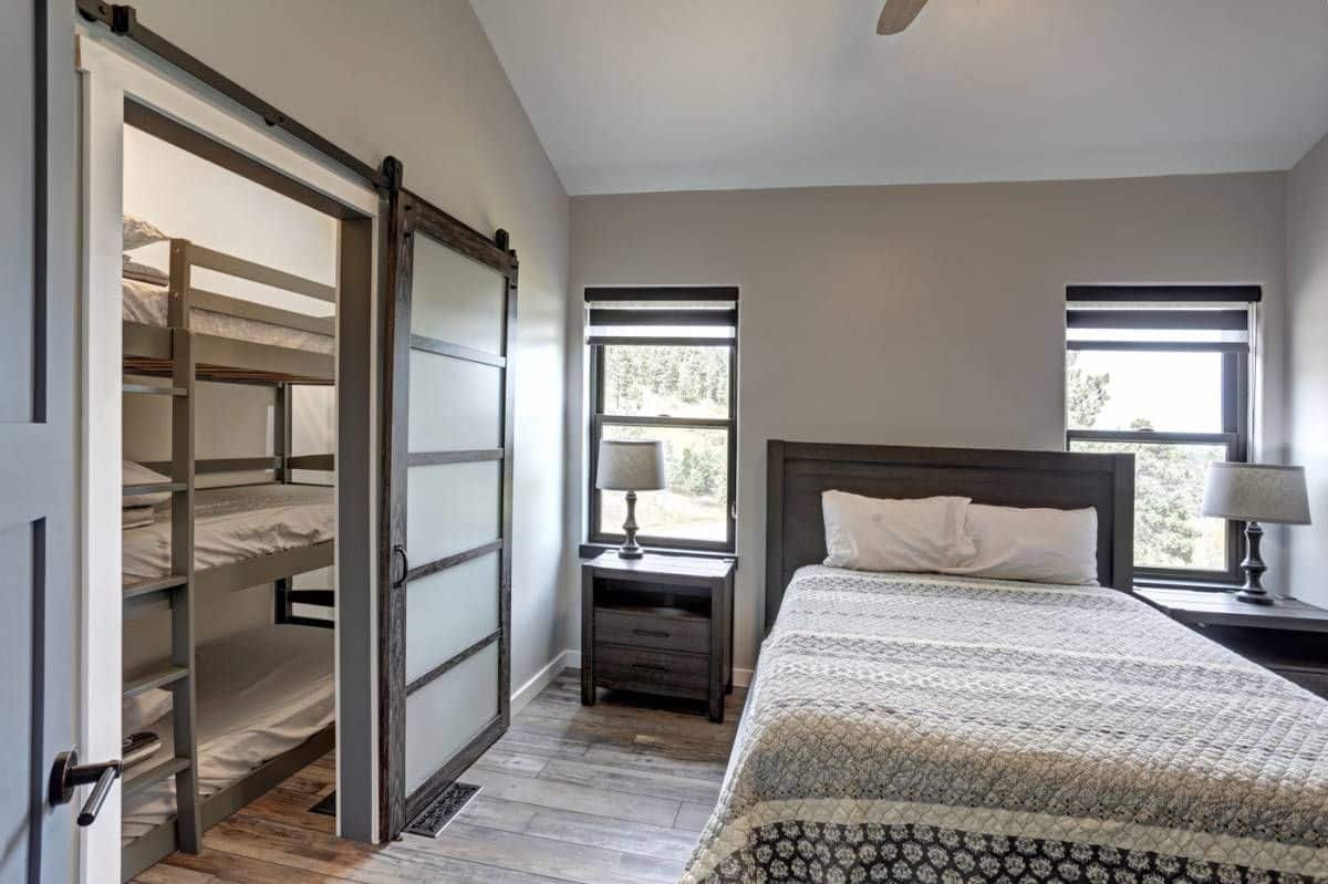 bed with white bedding against wall with open door to bunk room on left