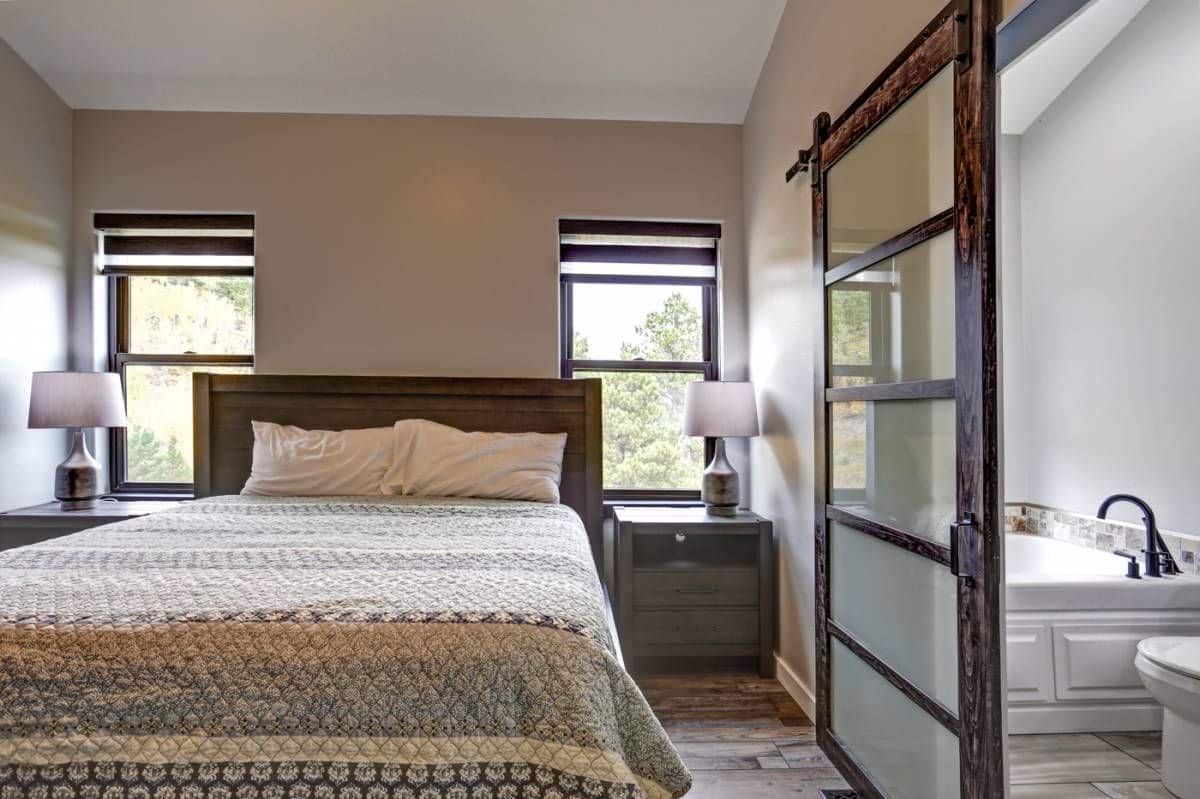 view into bedroom with striped white and gray bedding on bed beneath two windows