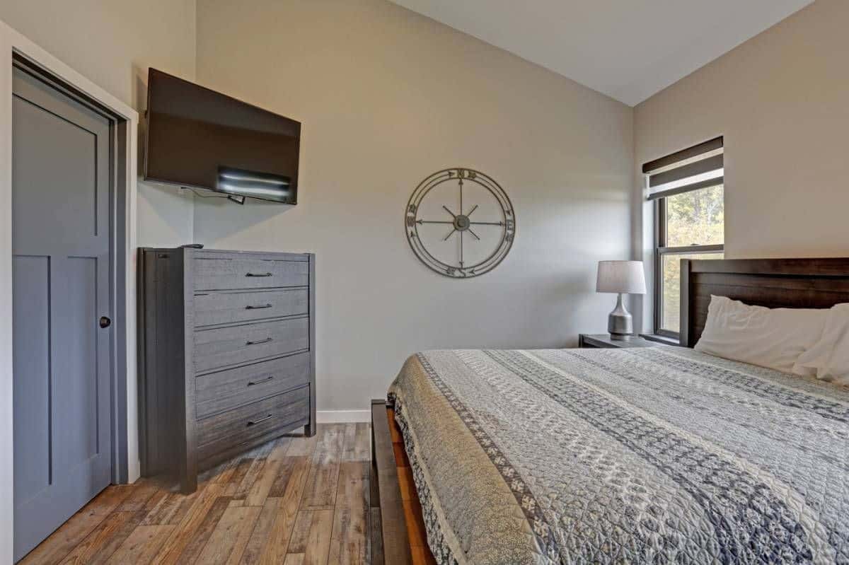 gray chest of drawers against wall beneath tv next to bed