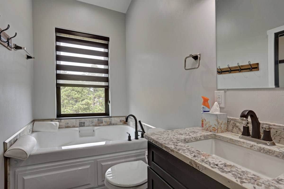 soaking bathtub with tile surrounding it below window