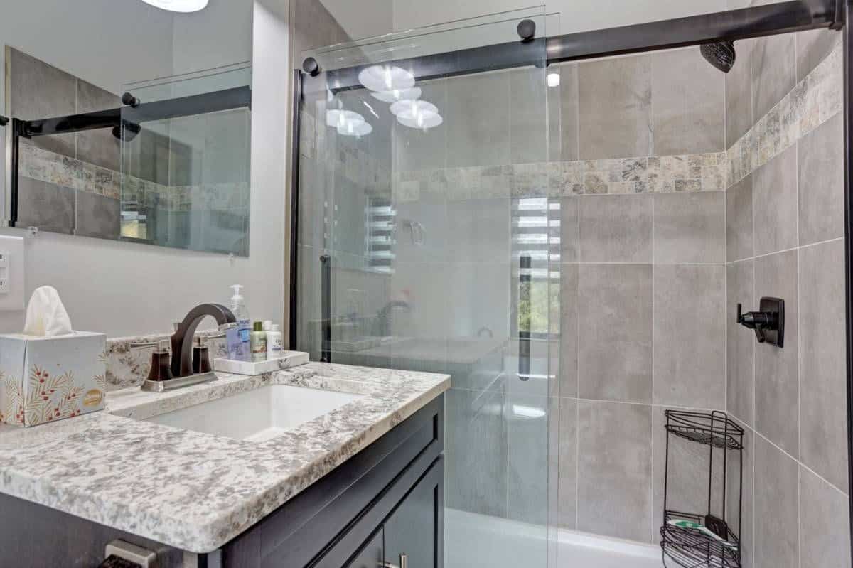 glass shower with tan tile and sink in foreground