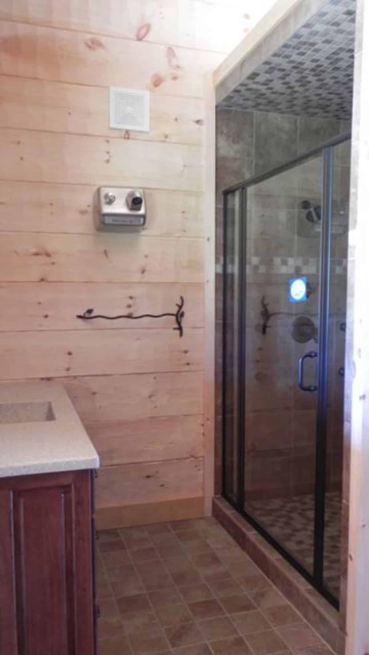 glass shower door on right with white vanity on left