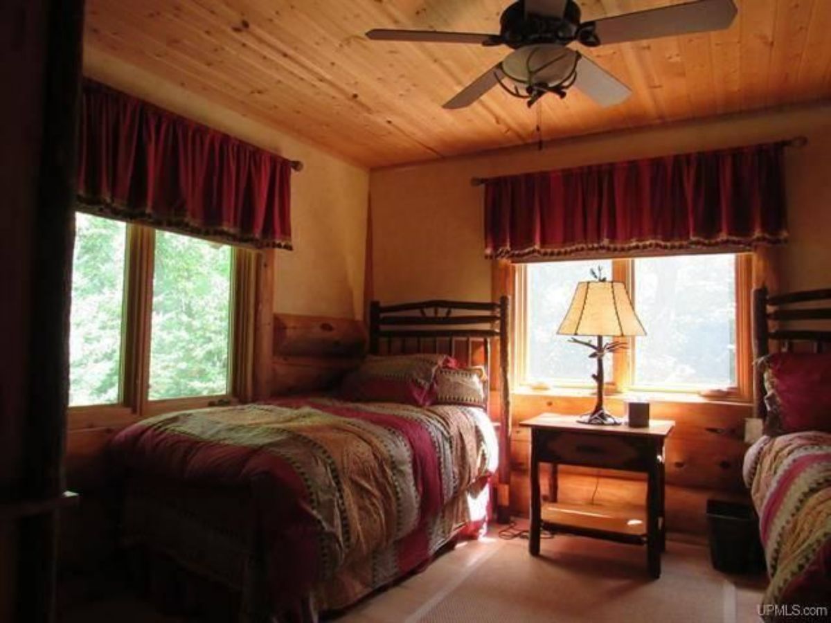 twin bed against wall with window and dark red curtains