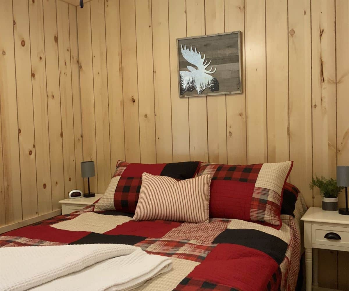red white and black bedding on bed underneath art on log wall