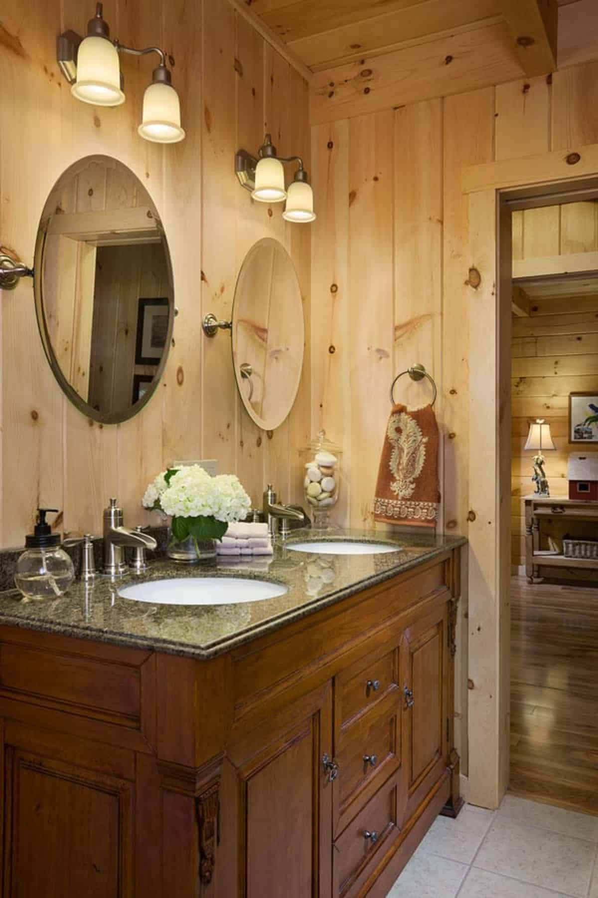 wood cabinet with white sink in bathroom with round mirrors above