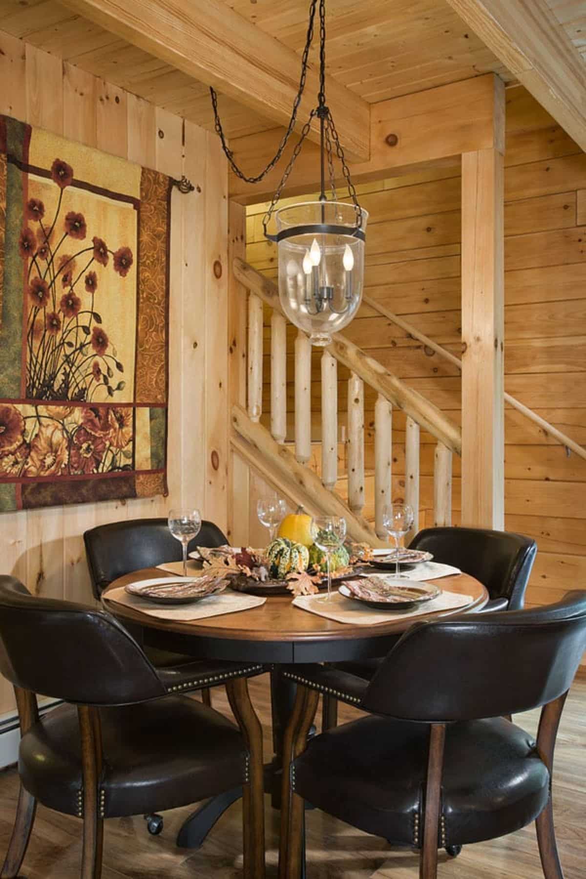 round dining table with black chairs in front of staircase