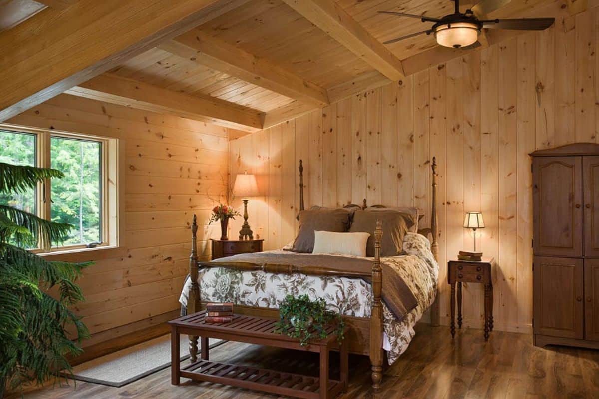 wood four poster bed under light wood ceiling