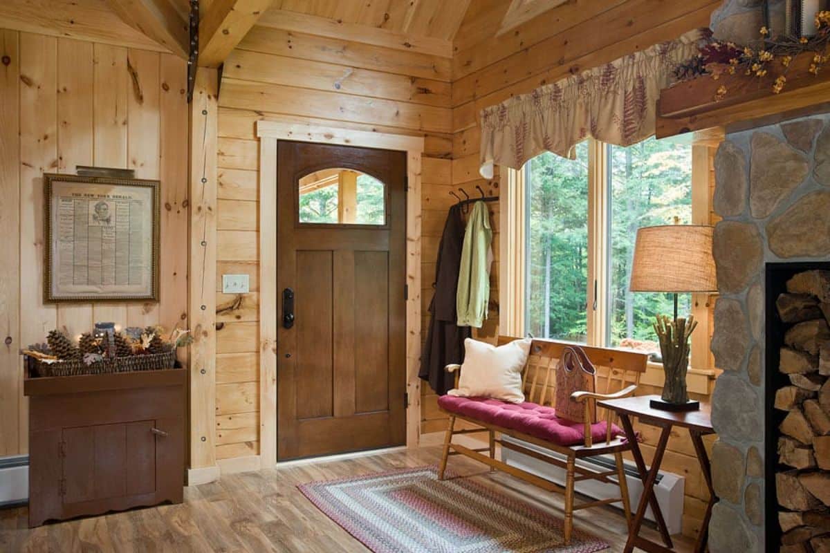 dark wood door leading into cabin with bench just inside door under window