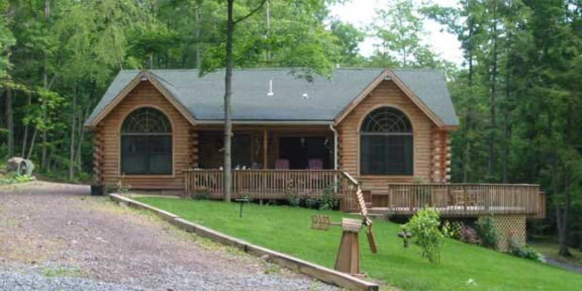 front of log cabin with large windows and alcoves on both ends