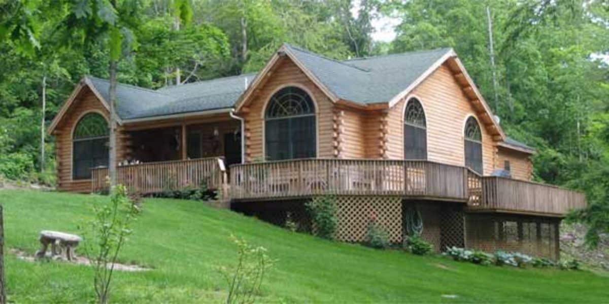 cabin on hill with porch on back and rounded windows