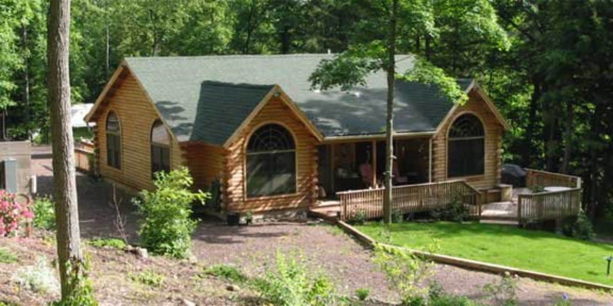 front of fairytale log cabin with rock drive and open windows on front