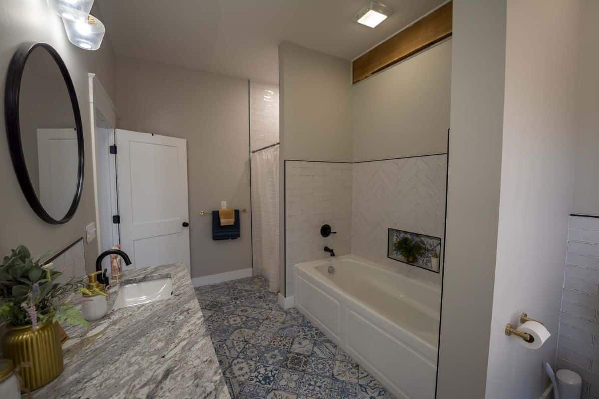 white bathtub and shower on right with gray counter on left in bathroom with light walls