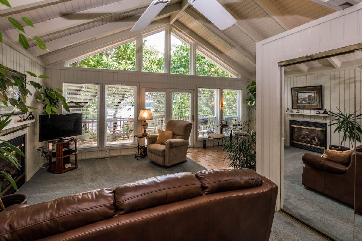 brown leather sofa in foreground with wall of windows at back