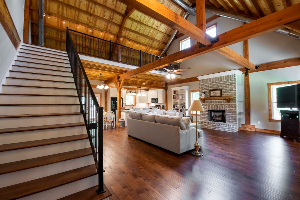 stairs to loft on left with black railing with living room on right