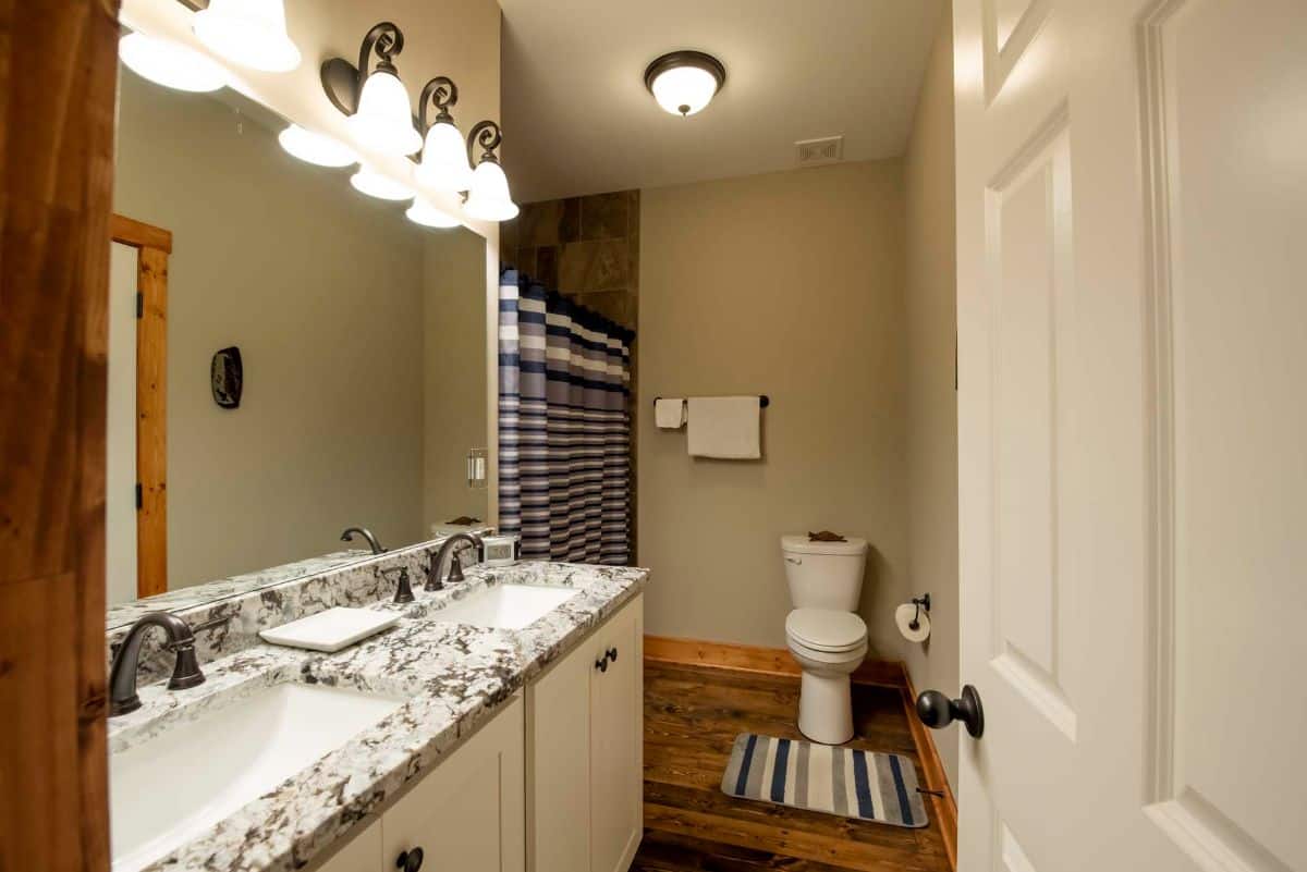 marble counter in bathroom with toilet against back wall and striped shower curtain on left