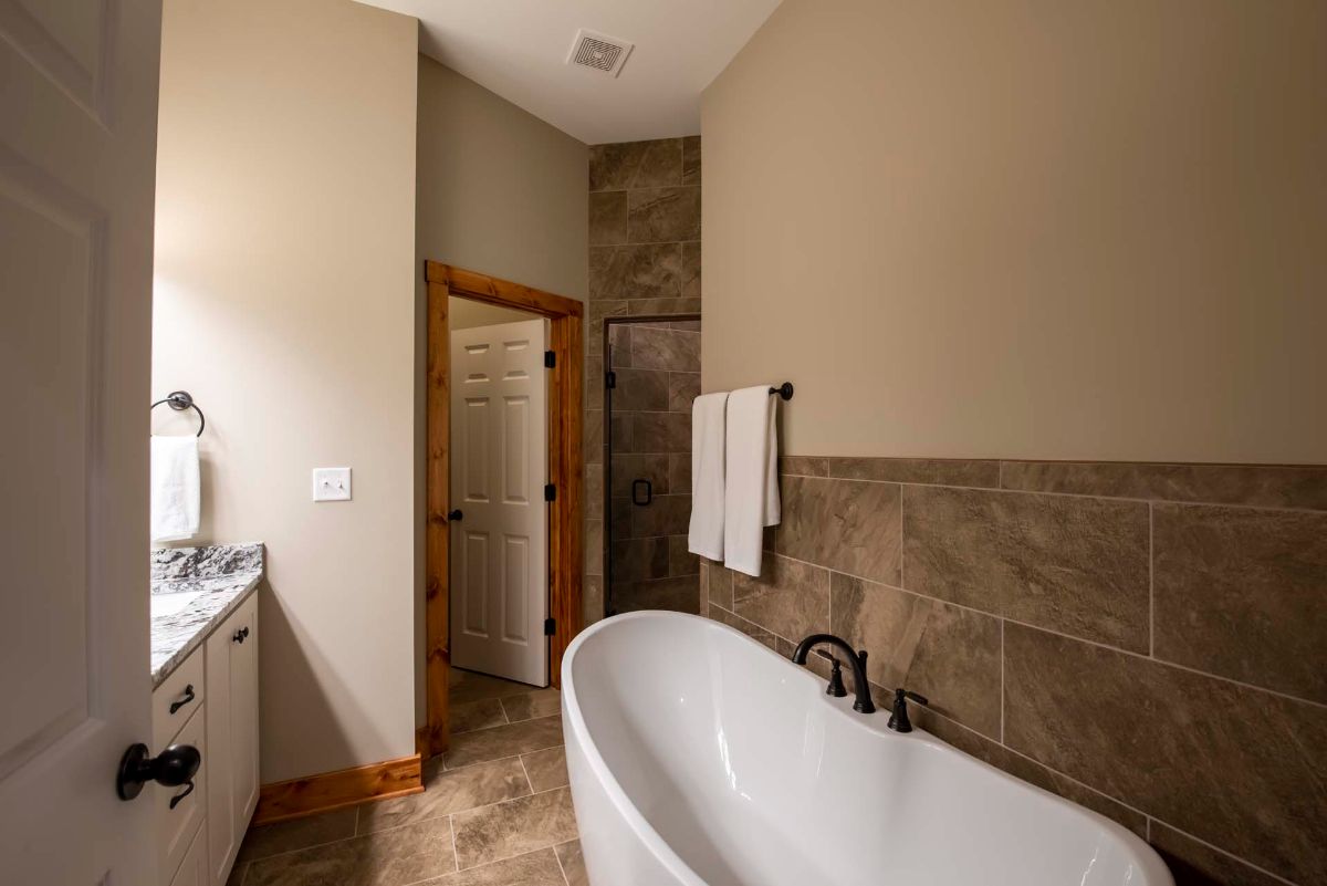 white soaking tub against tiled wall