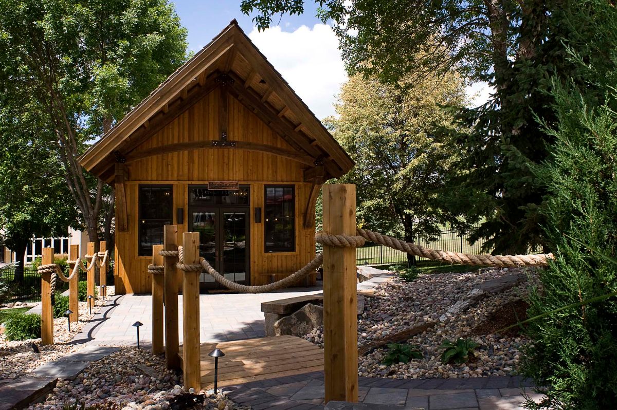 small log cabin with wooden beam bridge in front