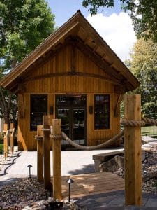 small log cabin with wooden beam bridge in front